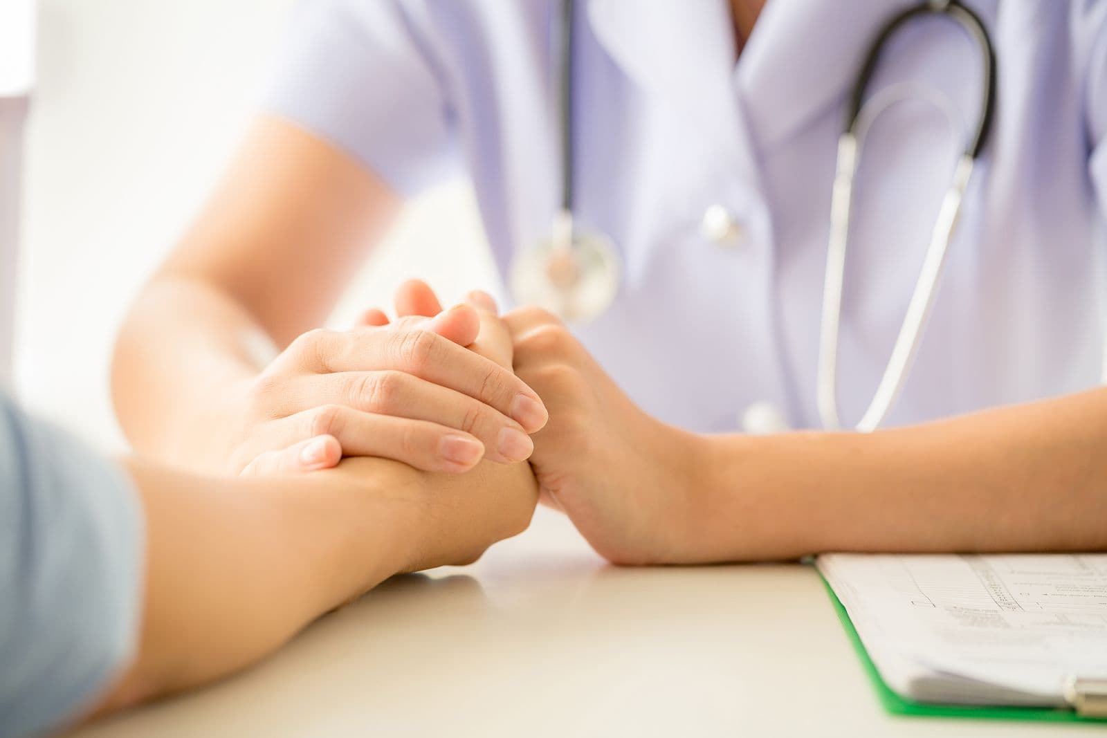 Nurse holding a patient's hand in reassurance